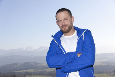 Portrait of man with arms crossed standing against sky