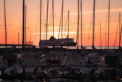 Sailboats moored at harbor against sky during sunset