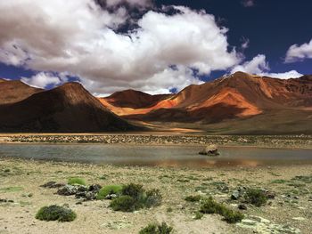 Scenic view of lake and mountains against cloudy sky