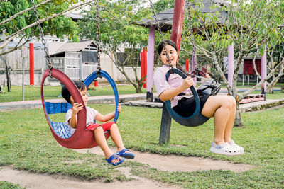 Full length of woman sitting on swing at park