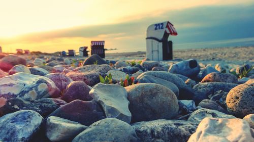 Rocks on beach against sky during sunset