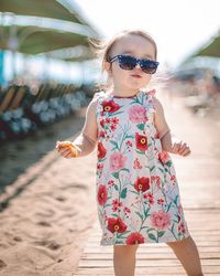 Portrait of girl in sunglasses standing at beach against sky