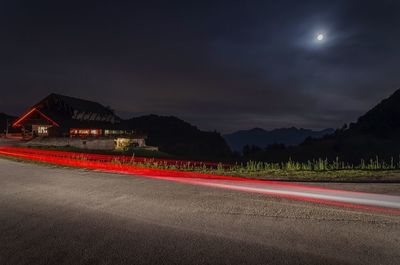 Light trails on road against sky at night