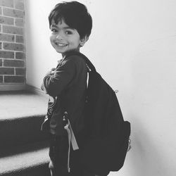 Portrait of smiling boy standing against wall