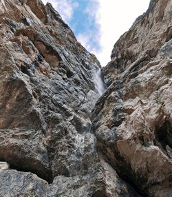 Low angle view of waterfall on mountain against sky