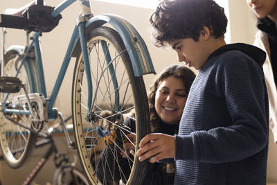 Boy learning bicycle repair with female technician at recycling center