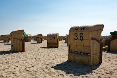 Hooded beach chairs on sand against sky