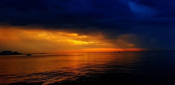 Scenic view of sea against dramatic sky during sunset