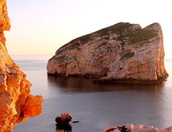 Rock formations in sea against clear sky