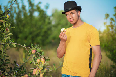 Young man wearing hat standing against plants
