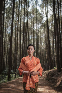 Portrait of smiling young woman standing in forest