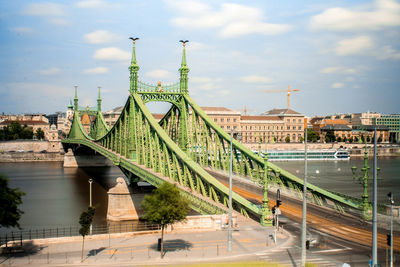 Bridge over river in city against cloudy sky