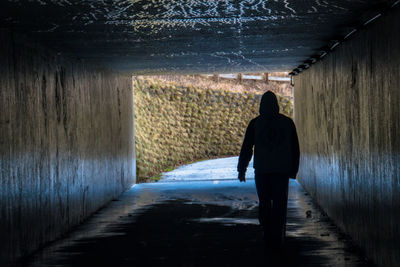 Rear view of man walking in tunnel