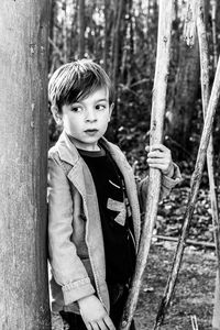 Portrait of boy standing on tree trunk