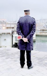 Rear view of man in uniform standing at promenade