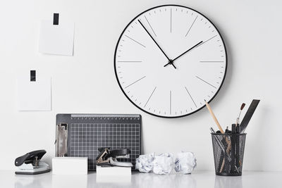 Clock on table against white wall