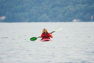 Rear view of woman kayaking in river