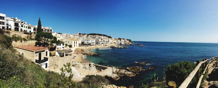 Scenic view of town by sea against clear sky