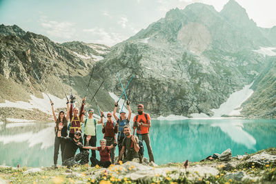 People standing by lake against mountains