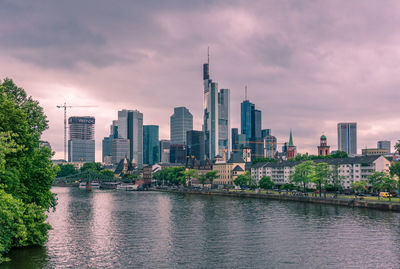 City at waterfront against cloudy sky