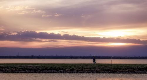 Man standing on field against sky during sunset