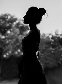 Side view of silhouette woman standing against sky