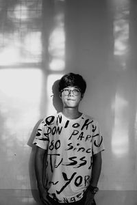 Portrait of young man standing against wall