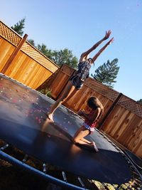 Sisters on trampoline in yard