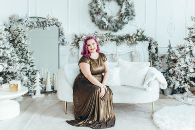 Portrait of young woman sitting on sofa at home