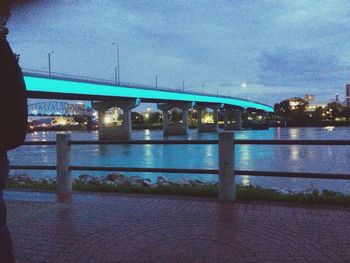 Illuminated bridge over river against sky in city at night