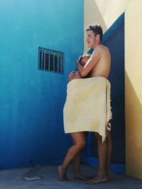 Couple wrapped in towel standing by wall