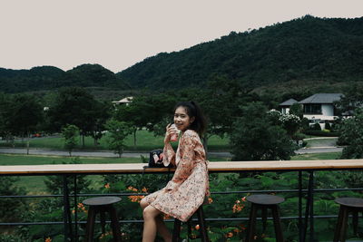 Portrait of smiling young woman against mountains