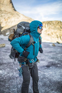 Mountain climber straps on heavy backpack during multi-day trip.