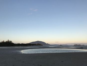 Scenic view of beach against clear sky during sunset