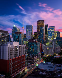 Illuminated buildings in city against cloudy sky