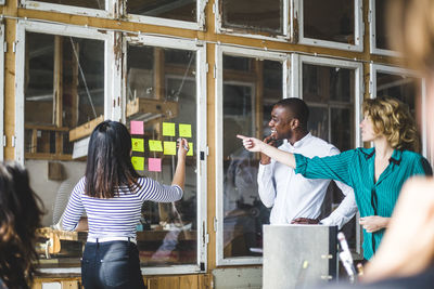 Confident computer programmers using adhesive notes to pen down their innovative ideas during meeting at workplace