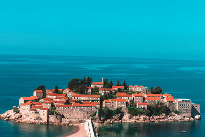 Buildings by sea against blue sky