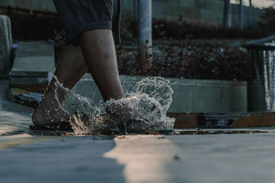 Low section of man standing by water