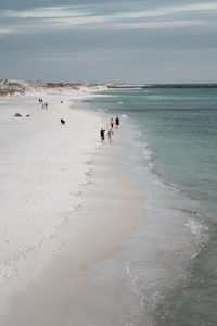 People walking the water's edge on the white sandy beaches of panama city, florida