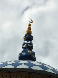 Low angle view of cross by building against sky