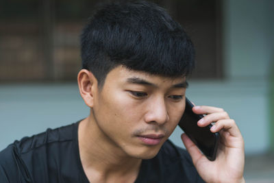 Close-up of serious young man talking over smart phone