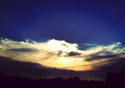 Silhouette of trees against cloudy sky