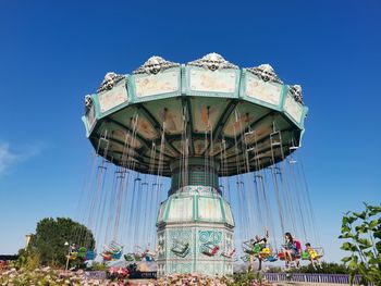 Low angle view of amusement park ride against blue sky