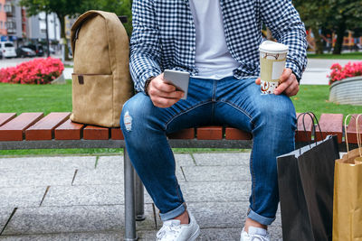 Full length of man sitting on bench in park