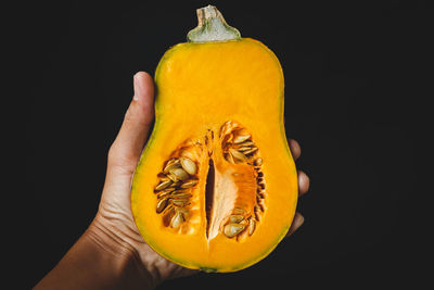 Close-up of hand holding fruit against black background