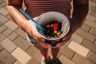 High angle view of a girl holding a bowl of ice cream with toppings