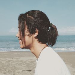 Portrait of young woman looking at sea against sky