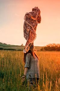 Woman with sarong standing in farm against sky