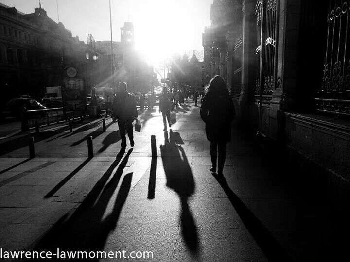 building exterior, architecture, built structure, city, walking, street, men, city life, lifestyles, sunlight, full length, person, rear view, city street, the way forward, leisure activity, transportation, shadow, building