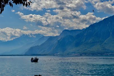 Boat sailing on sea against mountains